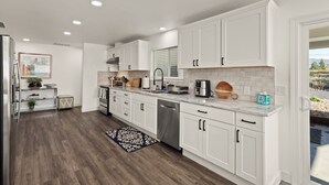Una cocina moderna con armarios blancos, electrodomésticos de acero inoxidable y piso de madera.