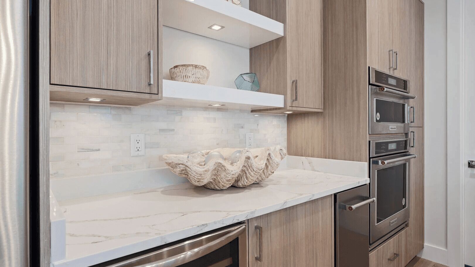 Una cocina con armarios de madera, encimera de mármol y electrodomésticos de acero inoxidable.