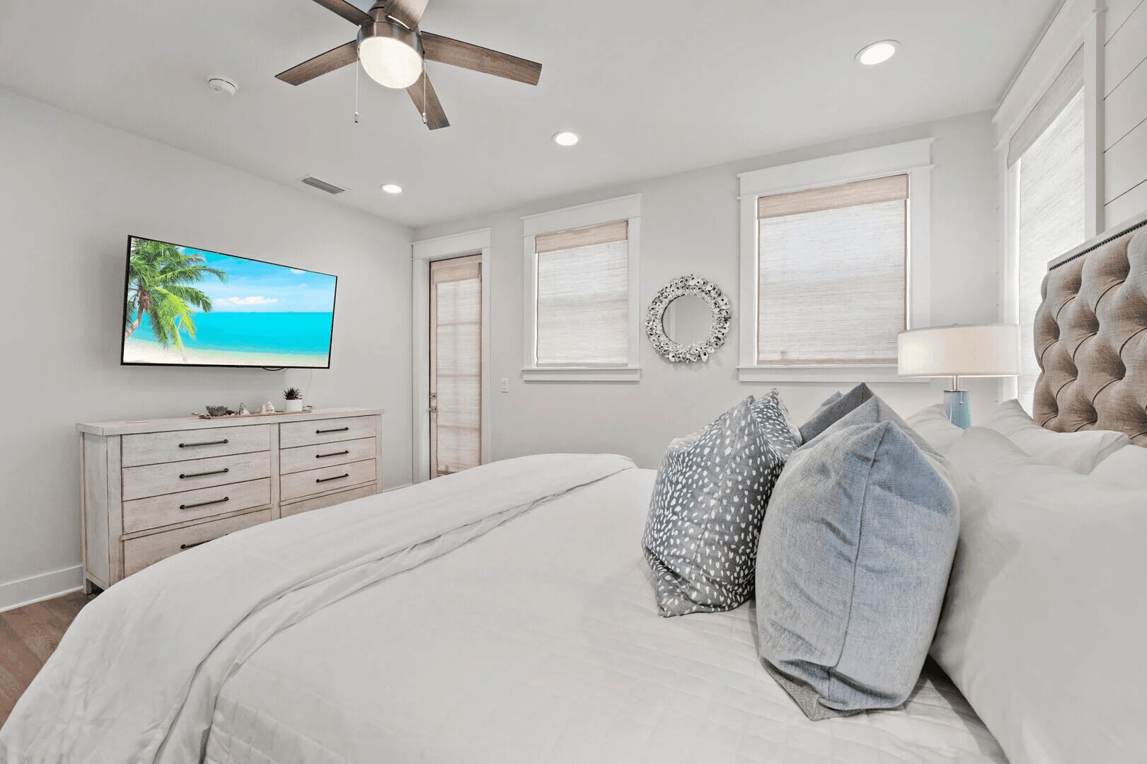 Un dormitorio con cama, cómoda, televisor y ventilador de techo.