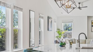 A modern kitchen with a central island, bar stools, and a pendant light fixture.