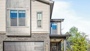 A two-story house with a garage, a front door, and a small front yard.