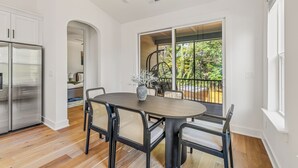 A modern kitchen with a large island, white cabinetry, and a stainless steel refrigerator.