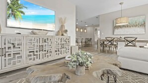 Un salon spacieux doté d’une grande télévision, d’un coin repas et d’un espace salon confortable.