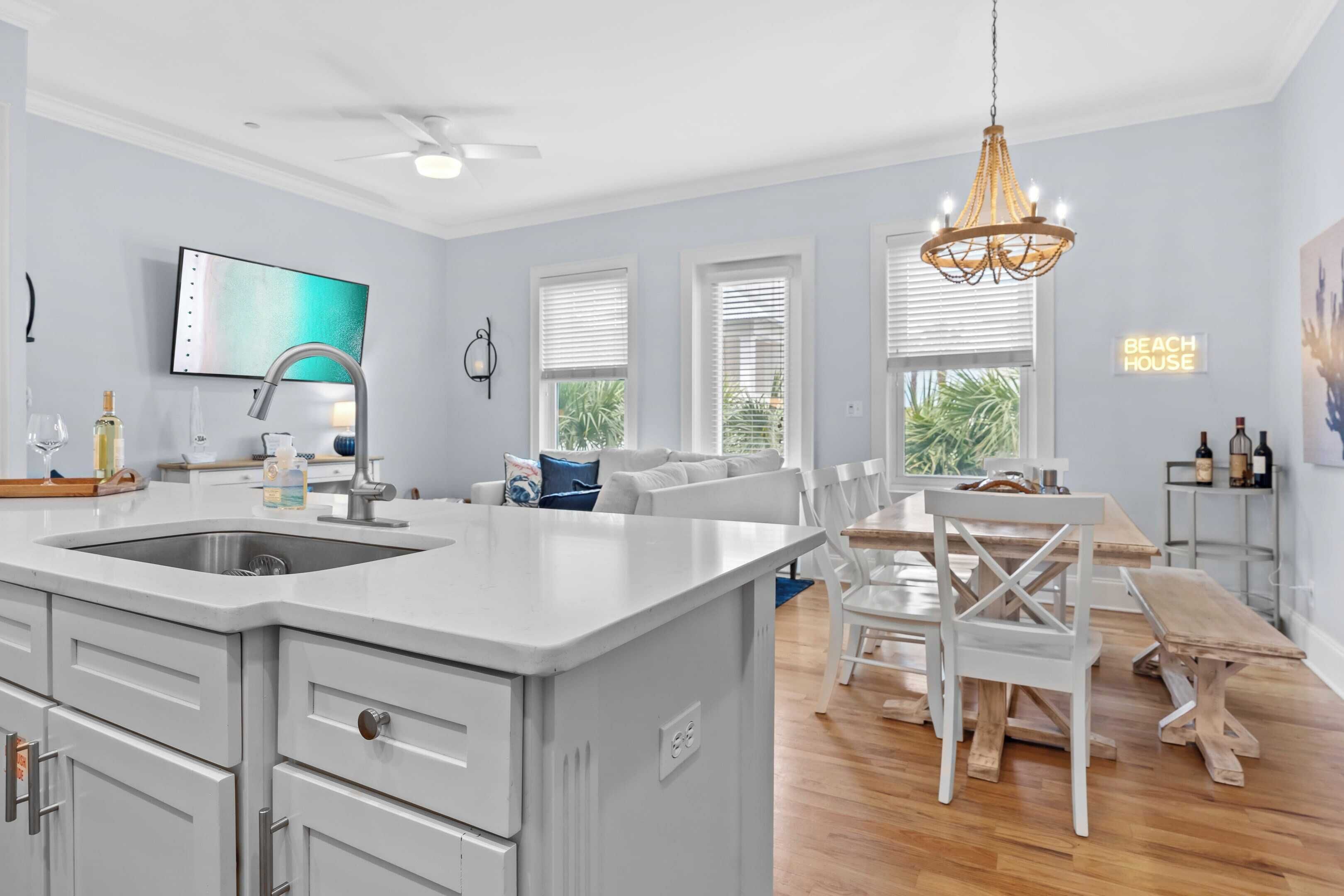 Une cuisine moderne dotée d’un grand îlot central, de meubles blancs et d’un ventilateur de plafond.