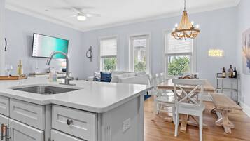 Une cuisine moderne dotée d’un grand îlot central, de meubles blancs et d’un ventilateur de plafond.
