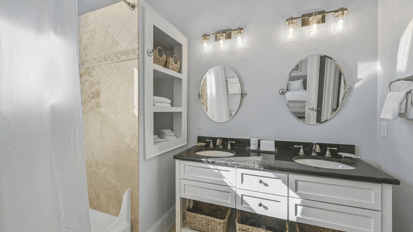 A bathroom with two sinks, a mirror, a towel rack, and a cabinet with baskets.