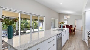 Uma cozinha moderna com uma ilha grande, armários brancos e um espaço de jantar com cadeiras vermelhas.