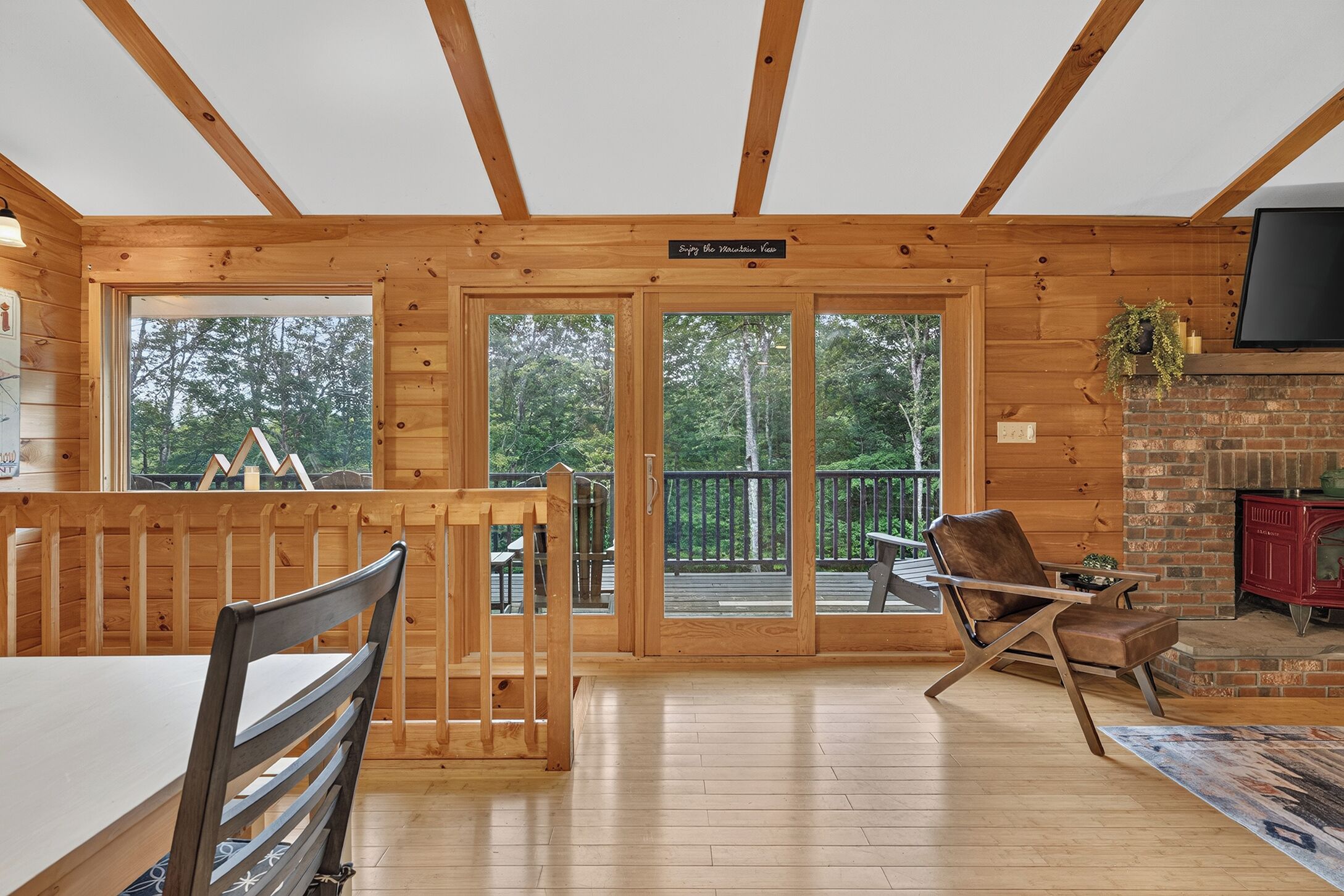 L’intérieur d’un chalet en bois comprend un coin repas, une cheminée et de grandes fenêtres donnant sur le paysage extérieur.