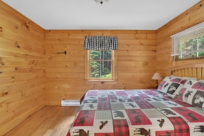 Une chambre dans une cabane en bois, avec un lit, une fenêtre et une vue sur les arbres.
