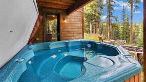 Un jacuzzi con plataforma de madera y vista a un bosque.