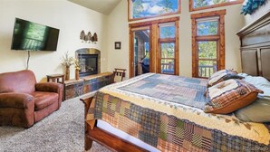Un dormitorio con una cama grande, chimenea, televisor y vista al exterior a través de una ventana.