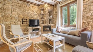 Un salon aux murs de pierre, doté d’un téléviseur, de canapés et d’une cheminée.