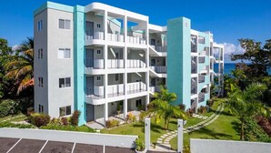 Un hotel moderno a più piani con balconi, una zona piscina e vista sull'oceano.