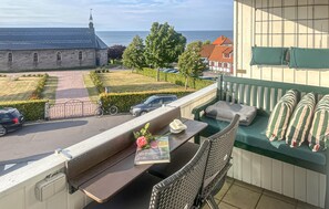 En balkong med utsikt över en kyrka, en häck och parkerade bilar.