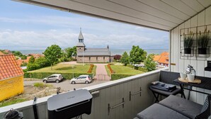 En balkon med udsigt til en kirke, en græsplæne og parkerede biler.