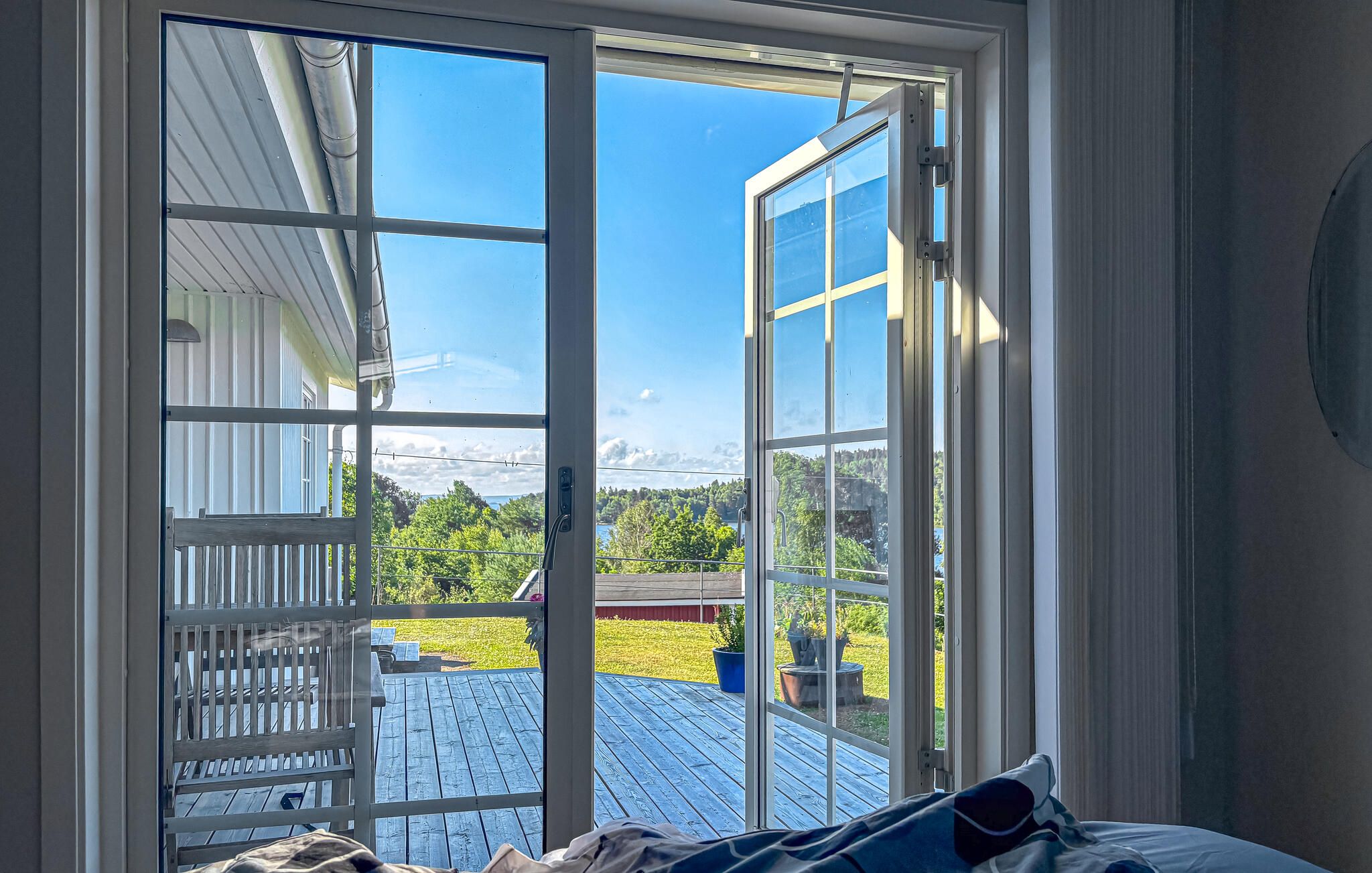 Una habitación con un amplio ventanal corredero que da a una terraza exterior con vistas a un paisaje montañoso.