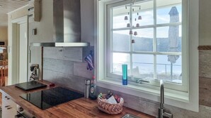 A modern kitchen with a large window, a built-in stove, and a hanging light fixture. - Cozy home in Kållekärr with WiFi (Kållekärr)