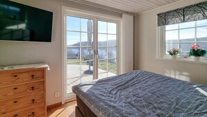 A bedroom with a bed, a dresser, a TV, a window with a view, and a curtain. - Cozy home in Kållekärr with WiFi (Kållekärr)