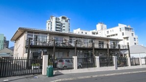 Un hotel de varios pisos con balcones, un estacionamiento y un cielo azul despejado.