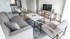 Un salón moderno con un sofá gris, una mesa de centro y un televisor sobre un mueble de madera.