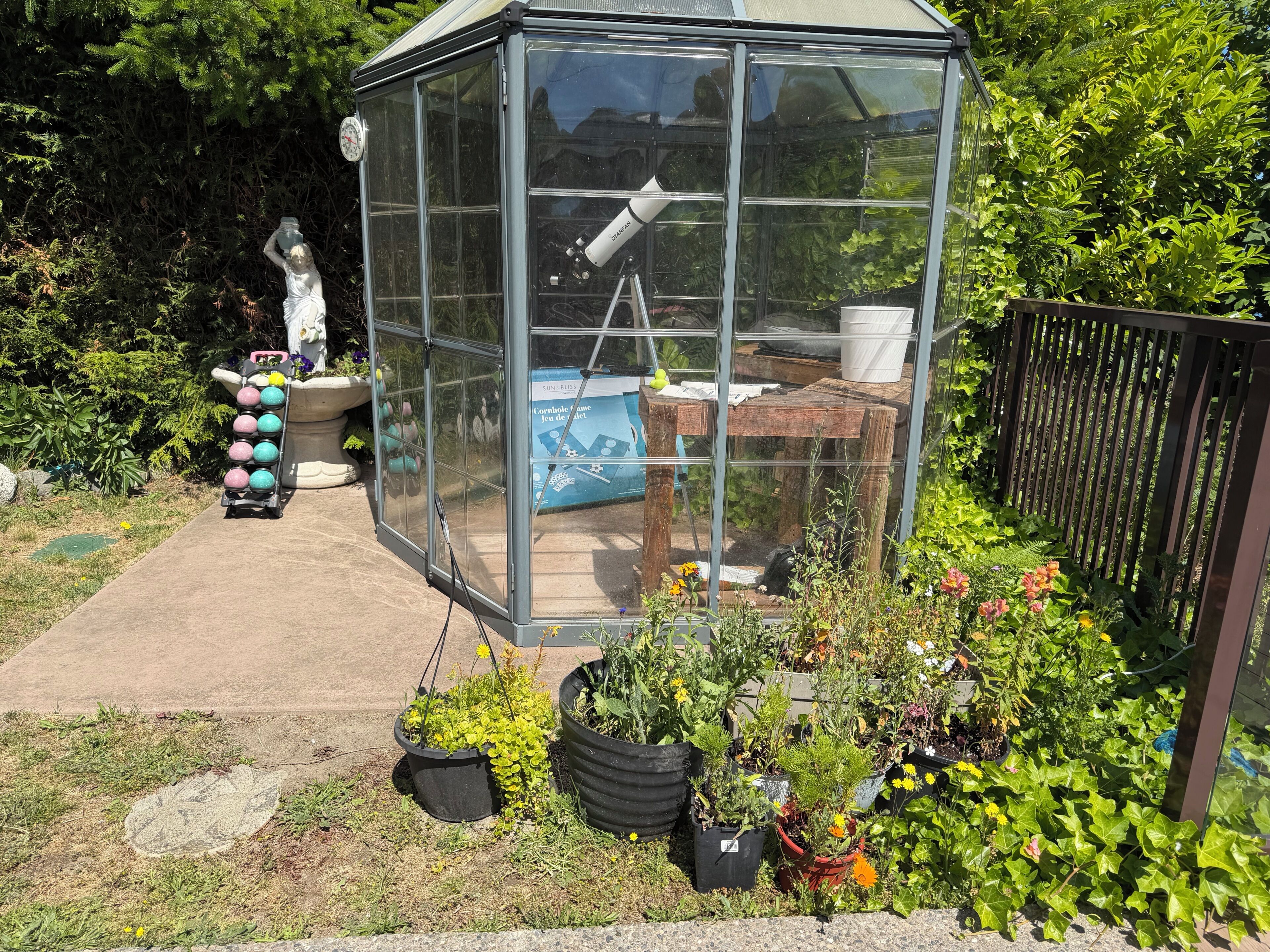 A greenhouse with a clear roof, a thermometer, and a table with a lamp.