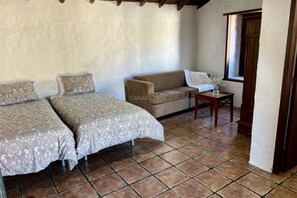 Une chambre avec deux lits, un canapé, une petite table et une fenêtre.