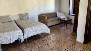 Una habitación con dos camas, un sofá, una mesita y una ventana.