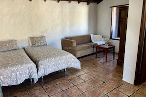 A room with two beds, a sofa, a small table, and a window. - Casa Pino: Relax and Nature with Stunning Views (Adeje)