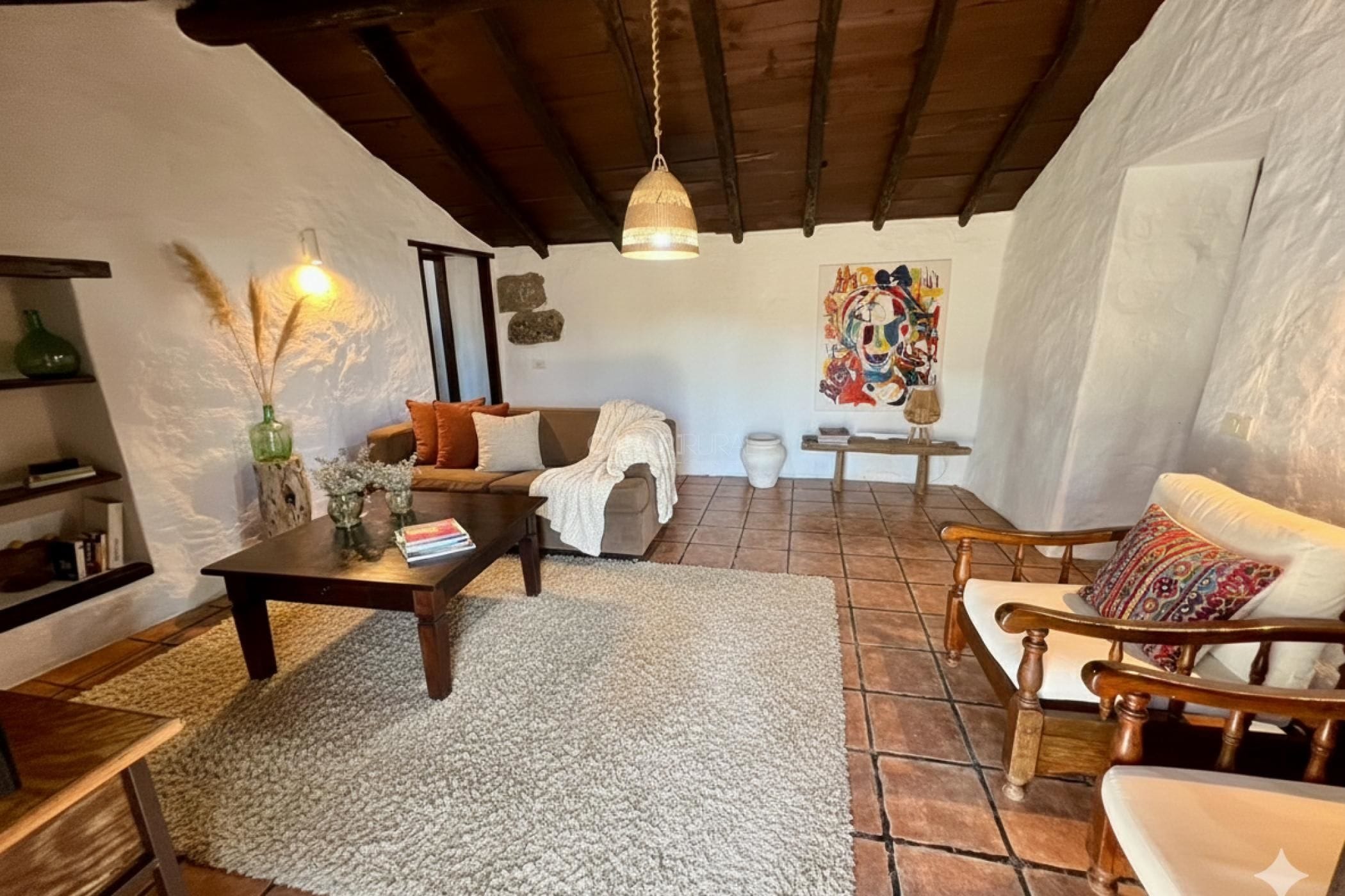 Una sala de estar acogedora con chimenea, un sofá, una mesa de centro y un sillón.