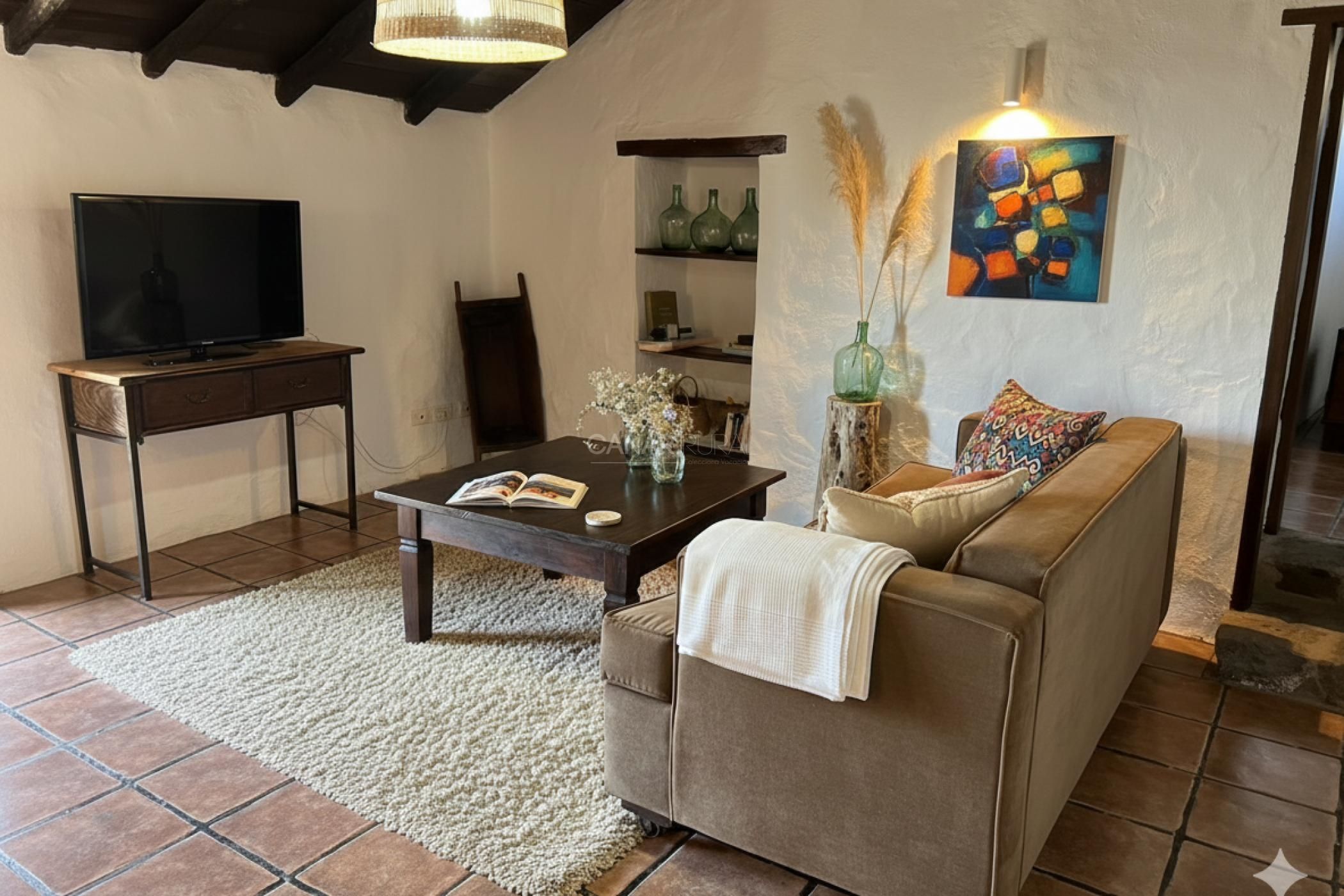 A living room with a sofa, coffee table, TV, and decorative items.