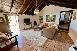 A living room with a sofa, a coffee table, a TV, and a painting on the wall.