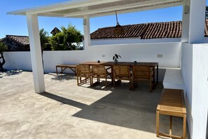 Eine Außenpatio mit Holztisch und -stühlen, einem Hocker und einer Pergola.