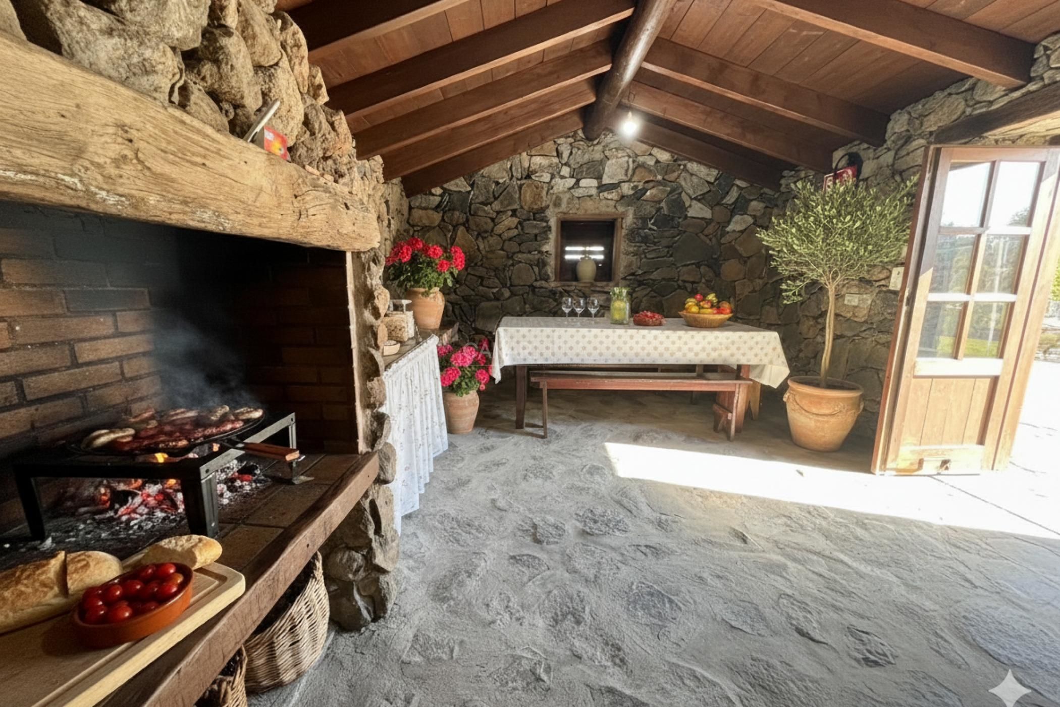 A rustic stone-walled room with a stone fireplace, a wooden table set with a white tablecloth, and a potted plant.