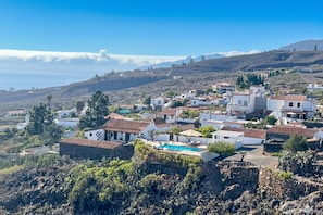 A coastal village with white buildings, a swimming pool, and a rocky landscape.