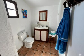 A bathroom with a toilet, sink, mirror, and towel rack.