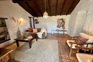 A cozy living room with a fireplace, a sofa, a coffee table, and a chair. - Stunning El Poleo Cottage at El Estanco Viejo: Historic Comfort With B (Adeje)