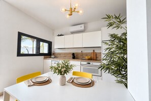 A modern kitchen with white cabinets, a wooden countertop, and a dining table set for two.