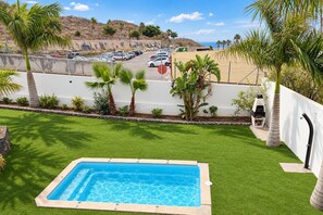 En swimmingpool med utsikt över en parkeringsplats och kullar i bakgrunden.