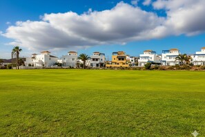 A residential area with houses, a green lawn, and a clear sky.