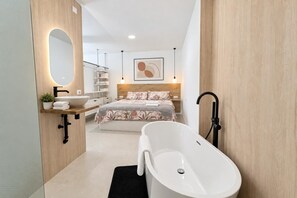 A modern bathroom with a freestanding bathtub, a large mirror, and a wooden vanity.