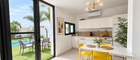 A modern kitchen with a dining area, large windows, and a view of a pool.