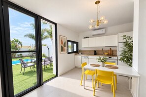 A modern kitchen with a dining area, large windows, and a view of a pool. - Live the experience of a stylish Loft! (Aldea Blanca)