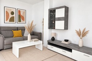 A modern living room with a grey sofa, white coffee table, and a grey cabinet with a glass shelf.
