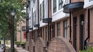 A row of brick buildings with a 'BAR' sign, a sidewalk, and a street lamp.