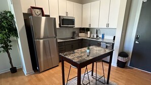 A modern kitchen with stainless steel appliances, a dining table, and a potted plant.