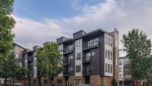 A modern multi-story residential building with balconies, a flat roof, and a mix of brick and concrete facades.