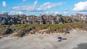 A beachfront property with multiple houses, a sandy beach, and some vegetation.