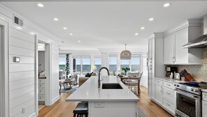 A modern kitchen with white cabinetry, a central island, and a view to the outside.