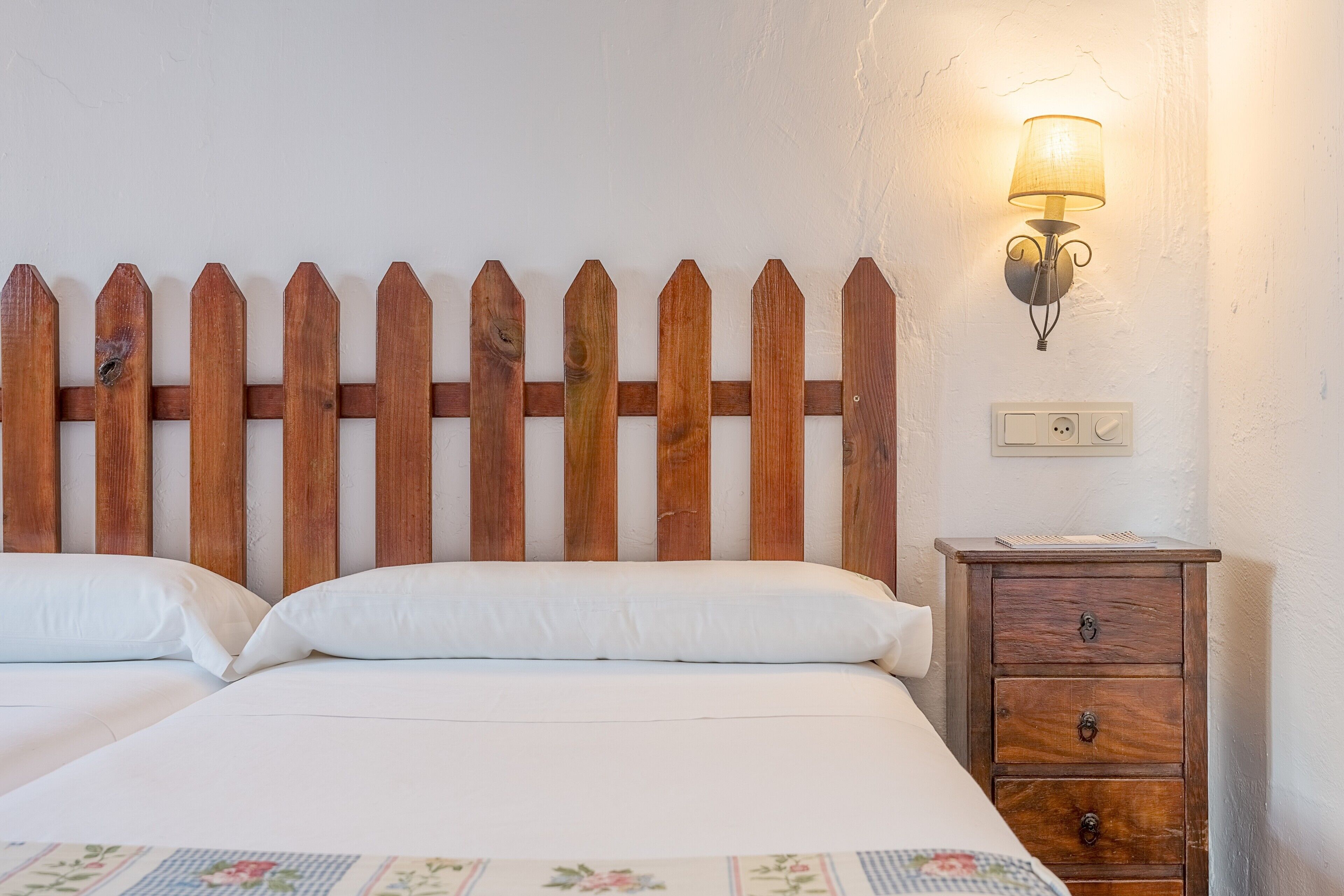 Un lit avec une tête de lit en bois, une lampe de chevet et une table de chevet dotée de tiroirs.