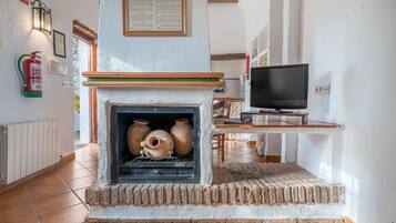 A fireplace with pottery, a television, and a fire extinguisher on the wall.